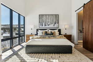 Bedroom with hardwood / wood-style flooring, a barn door, and a towering ceiling