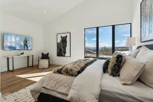 Bedroom with wood-type flooring and high vaulted ceiling