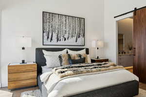 Bedroom with light hardwood / wood-style floors, a barn door, and ensuite bathroom