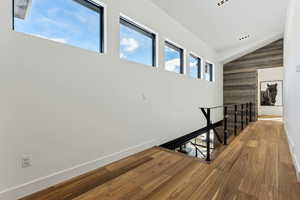 Hall with vaulted ceiling and hardwood / wood-style floors