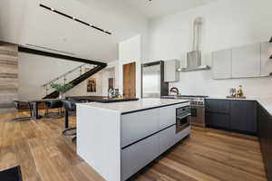 Kitchen with a breakfast bar area, white cabinets, premium appliances, hardwood / wood-style flooring, and a center island