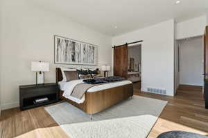 Bedroom featuring hardwood / wood-style flooring and a barn door