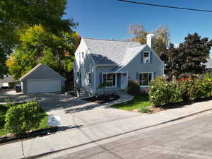 Cape cod house with a garage and an outbuilding