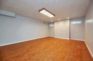 Basement with a textured ceiling and hardwood / wood-style flooring