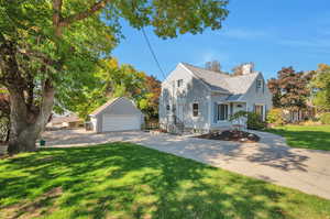 View of front of home with a front lawn, an outdoor structure, and a garage