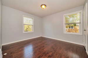 Empty room featuring a textured ceiling, dark wood-type flooring, and a wealth of natural light