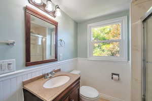 Bathroom featuring a textured ceiling, a shower with door, vanity, and toilet