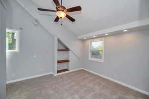 Interior space with ceiling fan, lofted ceiling, and carpet flooring