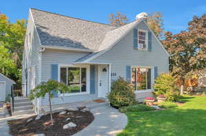 Cape cod-style house featuring cooling unit and a front lawn