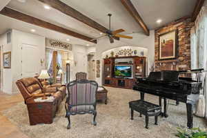 Tiled living room featuring ceiling fan and beam ceiling