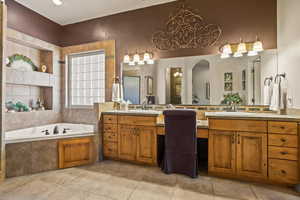 Bathroom with tile patterned flooring, tiled bath, a towering ceiling, and vanity