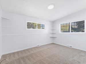 Carpeted spare room featuring vaulted ceiling