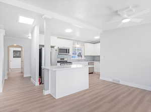 Kitchen featuring stainless steel appliances, white cabinetry, light hardwood / wood-style floors, and a kitchen island