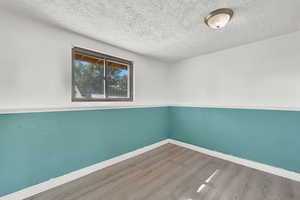 Spare room featuring wood-type flooring and a textured ceiling