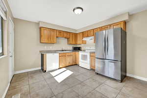 Kitchen with light tile patterned floors, stainless steel appliances, and sink