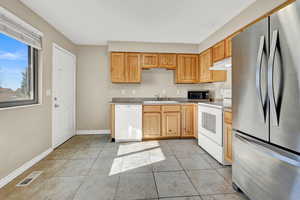 Kitchen with light tile patterned flooring, stainless steel appliances, sink, and light brown cabinetry