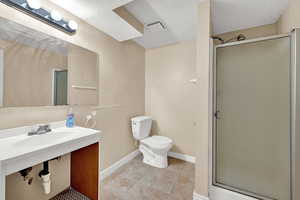 Bathroom featuring tile patterned floors, a textured ceiling, toilet, and walk in shower