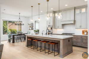 Kitchen with an island with sink, decorative light fixtures, light hardwood / wood-style flooring, appliances with stainless steel finishes, and a breakfast bar area