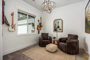 Living area featuring carpet floors, ornamental molding, and a chandelier