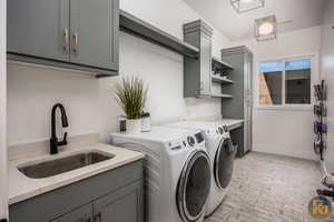 Washroom featuring washer and clothes dryer, cabinets, and sink