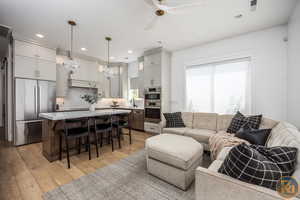 Living room featuring ceiling fan, light hardwood / wood-style flooring, and sink