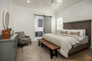 Bedroom with light hardwood / wood-style flooring, crown molding, wooden ceiling, ensuite bath, and a barn door