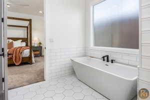 Bathroom with tile walls, tile patterned flooring, ornamental molding, and a washtub