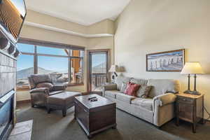 Living room featuring dark colored carpet, a mountain view, and a high ceiling