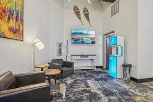 Carpeted living room featuring a towering ceiling