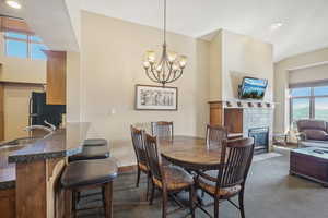 Carpeted dining area featuring a notable chandelier, a tile fireplace, sink, and plenty of natural light