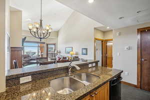 Kitchen featuring pendant lighting, sink, carpet, an inviting chandelier, and dark stone counters