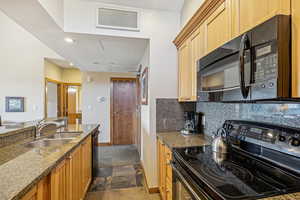 Kitchen featuring stone counters, sink, tasteful backsplash, and black appliances