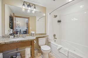 Full bathroom with vanity, tiled shower / bath combo, toilet, and tile patterned flooring