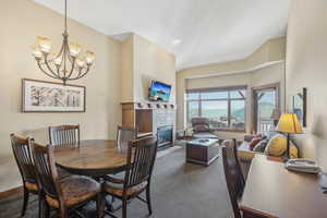 Dining area featuring dark carpet, lofted ceiling, a chandelier, and a tile fireplace