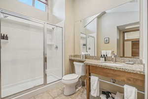 Bathroom featuring walk in shower, vanity, toilet, and tile patterned floors