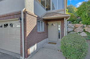 View of exterior entry featuring a balcony, a garage, and central AC