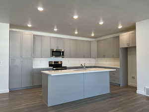 Kitchen with stainless steel appliances, a center island with sink, dark hardwood / wood-style floors, and sink