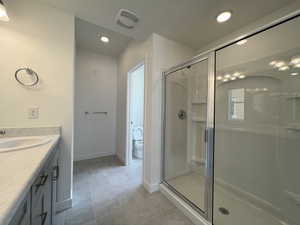 Bathroom featuring walk in shower, vanity, and toilet