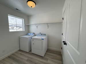 Laundry area with light wood-type flooring and separate washer and dryer