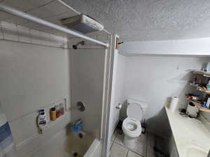 Full bathroom with tiled shower / bath, vanity, tile patterned flooring, and toilet