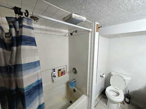 Bathroom with tile patterned flooring, toilet, and shower / bath combo