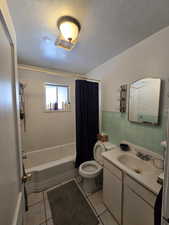 Full bathroom featuring vanity, toilet, shower / bathtub combination with curtain, and tile patterned floors