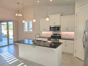 Kitchen featuring sink, appliances with stainless steel finishes, a kitchen bar, and white cabinetry