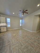 Unfurnished room featuring ceiling fan, a healthy amount of sunlight, and a textured ceiling