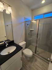 Bathroom with vanity, toilet, and an enclosed shower