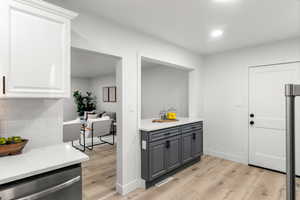 Kitchen featuring light hardwood / wood-style floors, gray cabinetry, stainless steel dishwasher, and white cabinetry