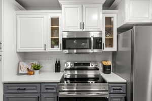 Kitchen featuring white cabinets, stainless steel appliances, and gray cabinetry