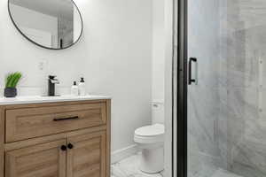 Bathroom featuring an enclosed shower, vanity, and toilet