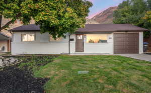 View of front of property with a yard and a garage