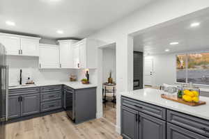 Kitchen featuring white cabinets, light hardwood / wood-style flooring, tasteful backsplash, and gray cabinetry